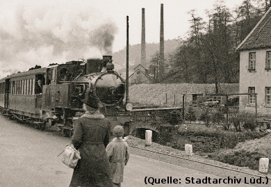 Foto: Eine Dampflokomotive zieht einen Zug durch ein Tal. Eine Mutter mit ihrem Kind ist auf dem Foto.